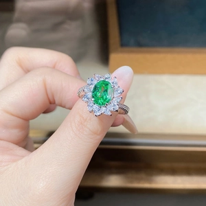 Close-up of sun flower silver ring featuring emerald cut green zircon and halo diamonds
