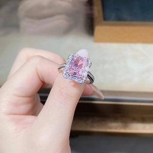 Macro detail of silver ring featuring a pink emerald-cut gemstone with diamond halo
