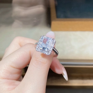 Close-up of radiant cut silver ring with pavé diamonds on a model's finger