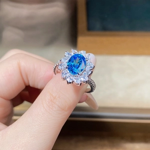 Macro shot of oval aquamarine silver ring with halo of petal-shaped zircon stones
