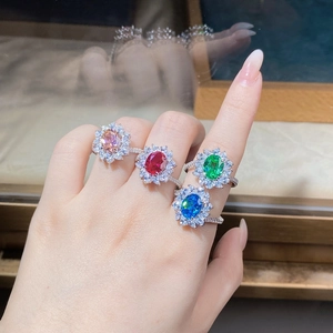 Close-up of four sunflower style silver rings with colorful oval cut gemstones on fingers