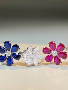 Macro shot of 925 silver rings with pear-cut zircon flower petals in blue, pink, and clear