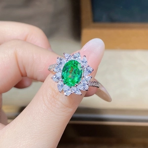 Detailed close-up of a flower-shaped ring with green stone and marquise-cut accents