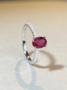 Macro shot of oval ruby ring with S925 silver four-prong setting and side accents