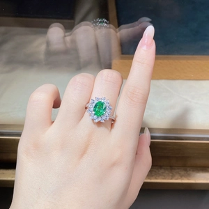 Detail of sunflower flower cluster ring featuring a green center stone and silver band