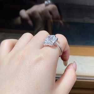 Macro side view of emerald cut diamond ring with halo setting on a silver band