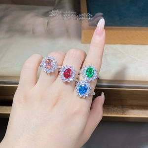Detailed view of colorful oval halo rings with sparkling cubic zirconia on fingers