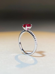 Macro side view of an oval red ruby silver ring with micro-paved sparkling diamonds