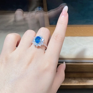 Detailed close-up of a flower-shaped ring with an oval blue stone and marquise zircons