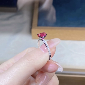 Detail of S925 silver ring with oval ruby and sparkling side stones held in fingers