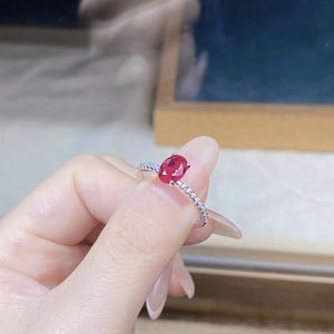 Detail of an S925 silver ring featuring a large oval ruby and micro-paved side stones