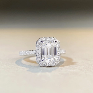 Vue macro d'une bague moissanite taille émeraude avec halo et diamants sur anneau argent