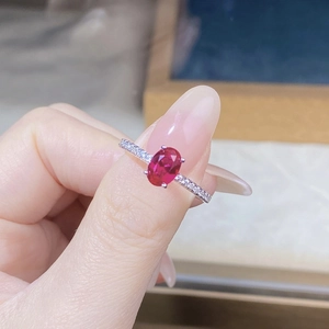 Macro view of a hand wearing an oval cut ruby ring with sparkling side stones