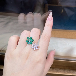 Detail view of a dual flower ring with green and clear zircon stones on a model hand