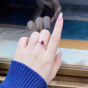Close-up of S925 sterling silver ring with oval ruby and micro-pave diamonds on finger