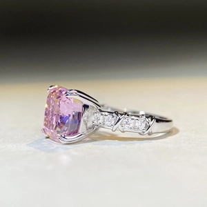 Macro detail of pink cushion-cut gemstone ring with crisscross silver band and diamonds