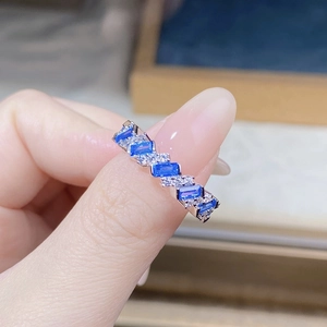 Macro view of blue rectangular gemstones and round diamonds set in a silver ring band