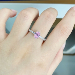 Close-up of a pink oval gemstone ring with pavé side stones on the silver band