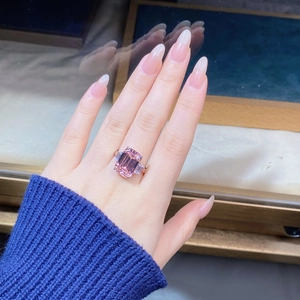 Close-up of luxury 925 silver ring featuring emerald-cut pink sapphire on a finger