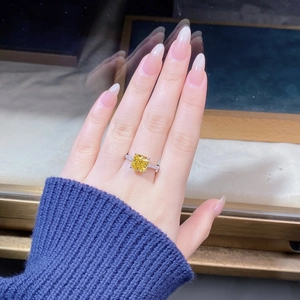 Macro shot of square cut yellow diamond ring with micro-pave diamond band on finger