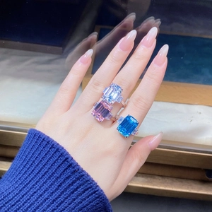 Detailed view of emerald-cut aquamarine and colorful gemstone rings on a finger