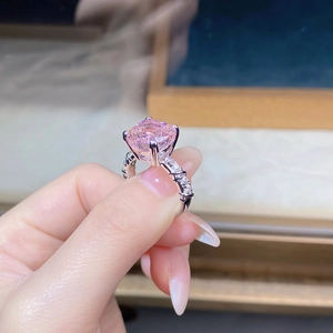 Close-up of square cut pink diamond ring with sparkling paved silver band on finger