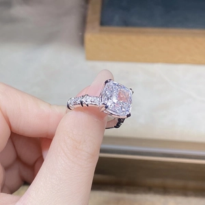 Macro shot of cushion-cut solitaire ring with four-prong setting and pavé diamond band