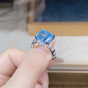 Macro shot of a large square blue gem ring in silver setting with side accent diamonds