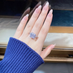 Detailed view of a cushion cut cubic zirconia ring with side stones on a finger