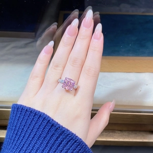 Close-up of cushion cut pink diamond ring on hand with elegant crossover silver band