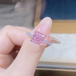 Macro view of a pink cushion-cut gemstone set in a four-claw silver ring with side stones