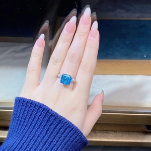 Detailed close-up of a cushion-cut blue sapphire silver ring worn on a hand