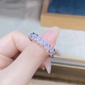 Close-up of a silver band ring with alternating baguette and round zircon stones on a hand