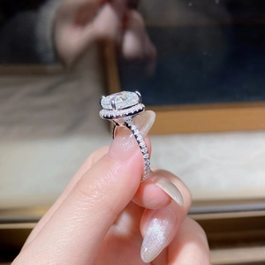 Macro detail of oval cut moissanite ring with halo setting and pavé diamond band