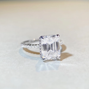Macro shot of emerald cut moissanite ring with pave set stones on silver band