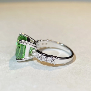Macro detail of emerald-cut green stone with crisscross silver band and zircon accents
