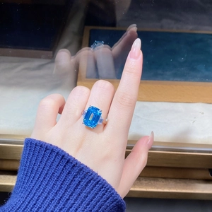 Close-up of emerald cut aquamarine ring with side stones worn on finger