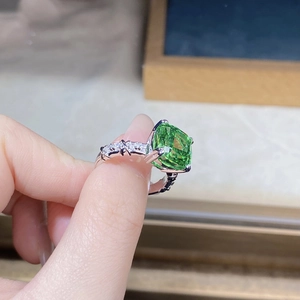 Macro detail of cushion-cut green gemstone ring with pavé diamond twisted silver band