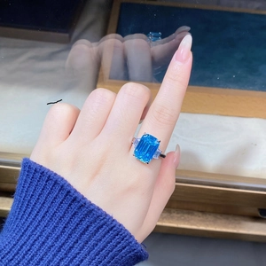Macro view of aquamarine emerald-cut ring with side baguette stones on a finger