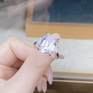 Macro shot of emerald cut square sparkling ring with four-prong silver setting on finger