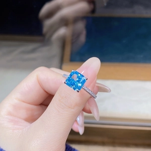 Close-up of square cut blue gemstone ring with pave-set accents on silver band