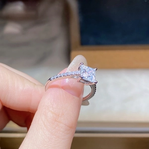 Macro shot of princess cut moissanite ring with four-prong setting and side diamonds