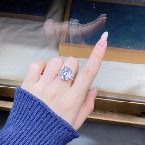 Macro shot of an emerald cut three-stone silver ring worn on a finger in a jewelry shop
