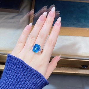 Detail shot of emerald-cut aquamarine blue gemstone ring with baguette side stones