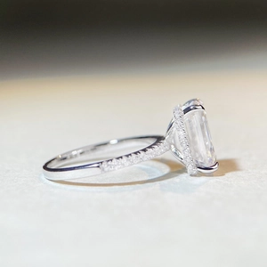 Side view detail of a 4 carat emerald cut moissanite halo ring with micro-pave silver band