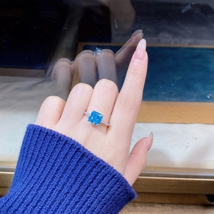 Close-up of cushion-cut blue zircon silver ring with pavé diamonds on model hand