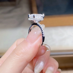 Close-up of 4-carat emerald cut moissanite ring with side-set pavé diamonds in silver