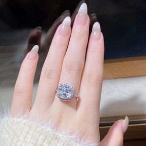 Macro shot of 5 carat cushion cut moissanite ring with halo setting on a model finger