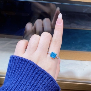 Macro view of square blue gemstone ring with pave diamonds on a silver band