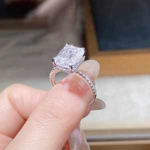 Macro detail of 4ct emerald cut moissanite ring with halo setting and side stones
